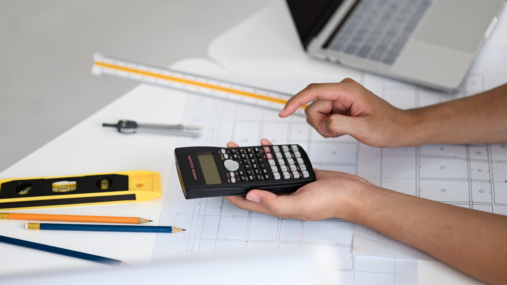 Hand using on calculator, engineers use a calculator to calculate house plans.