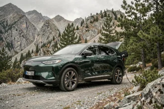 SUV électrique 4x4 en recharge sur un chemin de montagne entouré de forêt de pins et de rochers