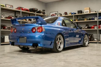 Nissan Skyline GT-R R34 Bayside Blue en vue 3/4 arrière dans un garage de collection privé